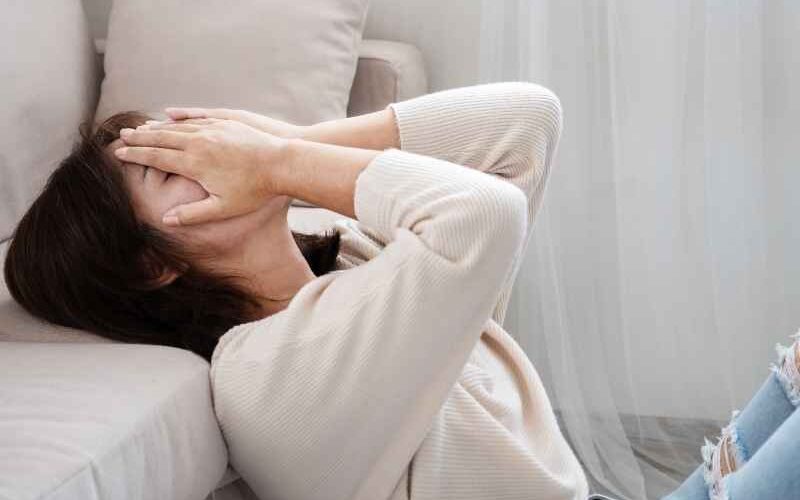 Persona sentada en el suelo cubriéndose el rostro con las manos, reflejando ansiedad y miedo relacionado con la salud y el diagnóstico de VIH.