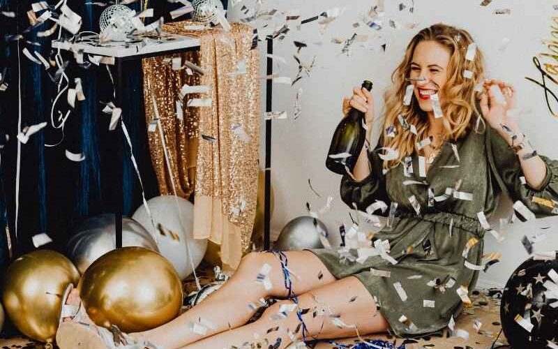 Mujer celebrando Año Nuevo con confeti, simbolizando el inicio de nuevos propósitos.