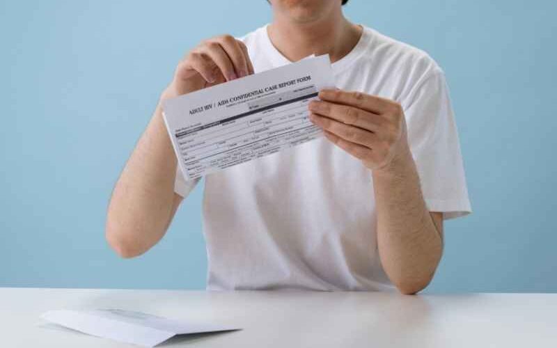 Persona sosteniendo y leyendo un documento tipo resultado o formulario de prueba de VIH, en un entorno clínico.