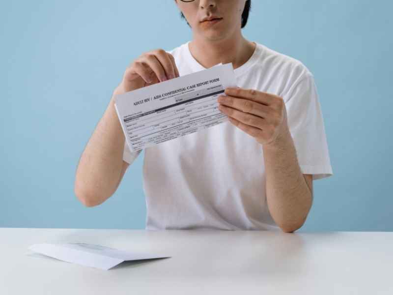 Persona sosteniendo y leyendo un documento tipo resultado o formulario de prueba de VIH, en un entorno clínico.